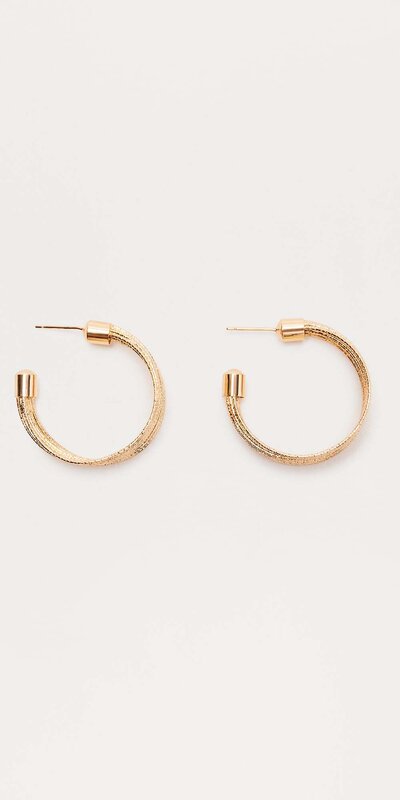 Zlaté kruhové náušnice s detailom kovovej štruktúry Zlatá